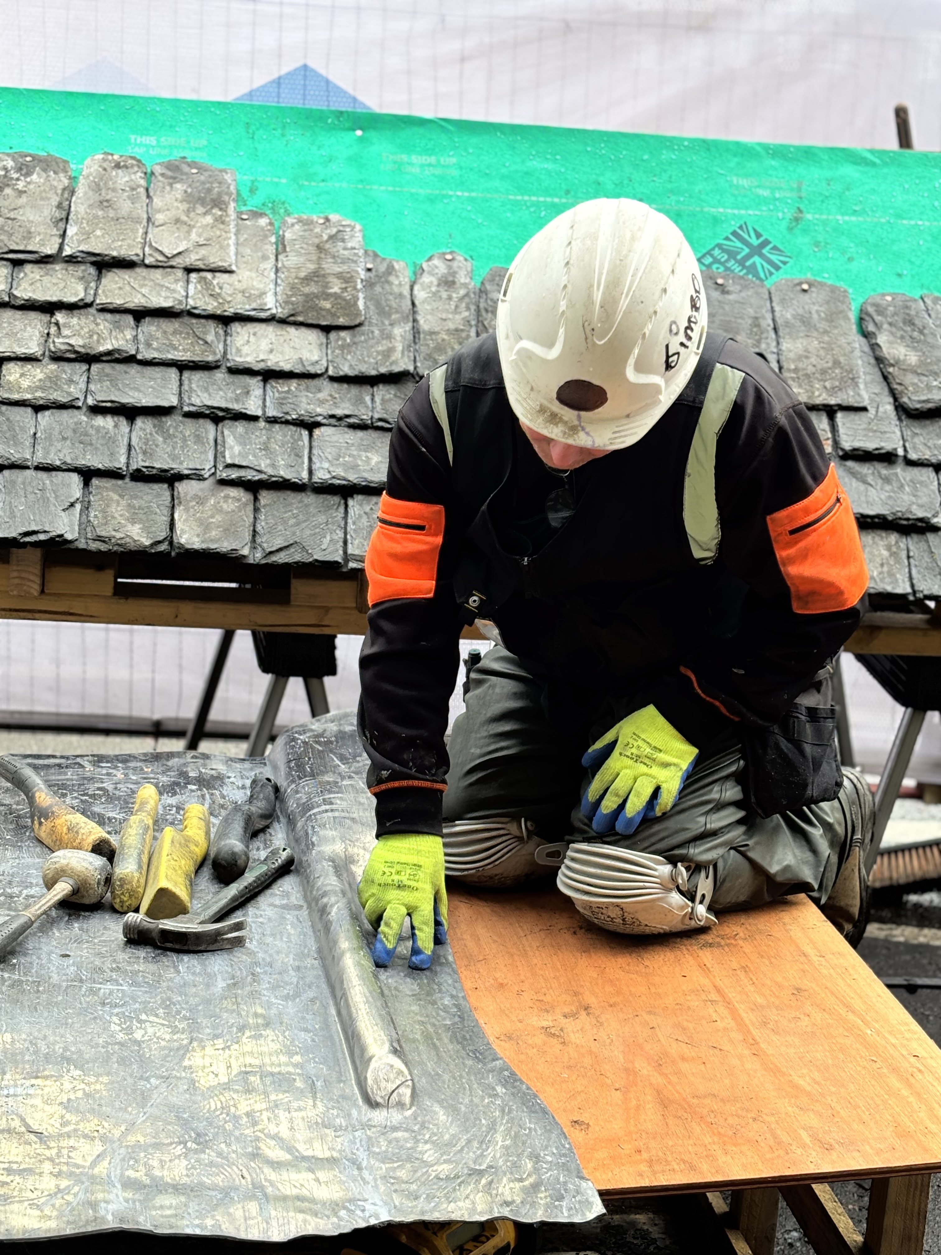 perienced roofer demonstrating lead pipe weathering techniques to attendees at a Roofing Advisors traditional roofing skills day