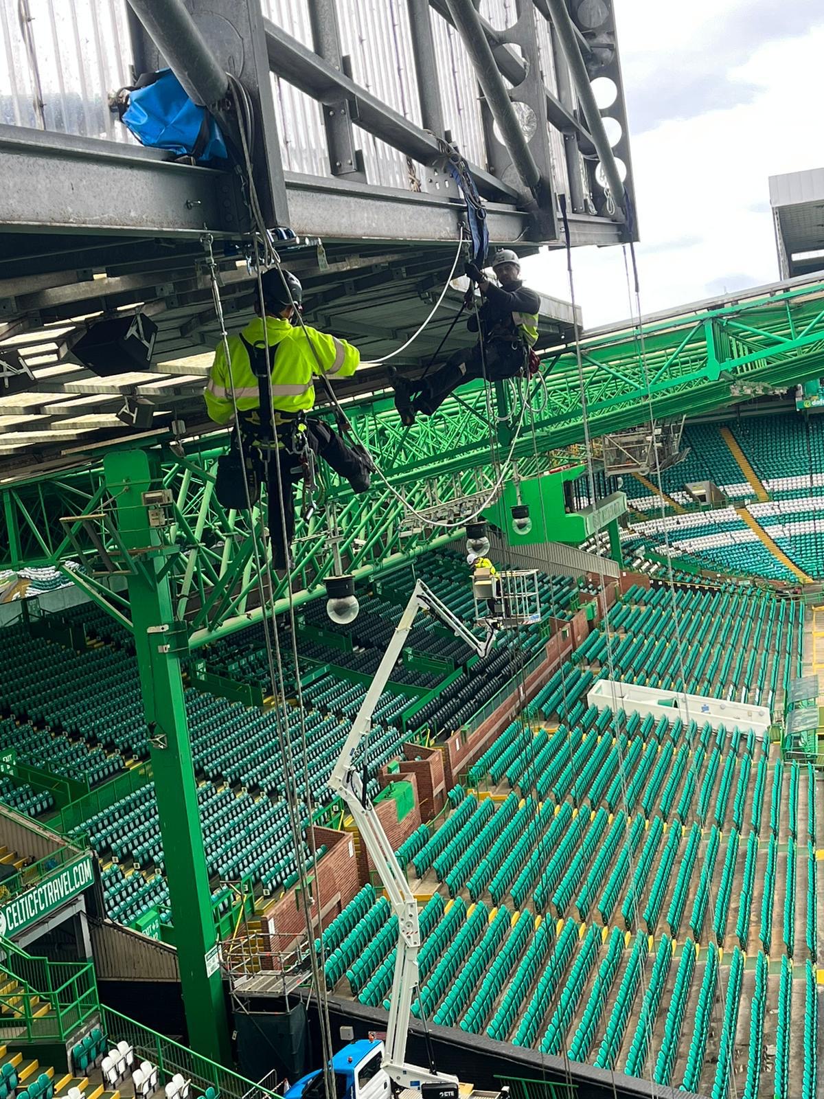Roofing Advisors rope access team working on the roof steelwork structure at Celtic Park during maintenance and netting installation works