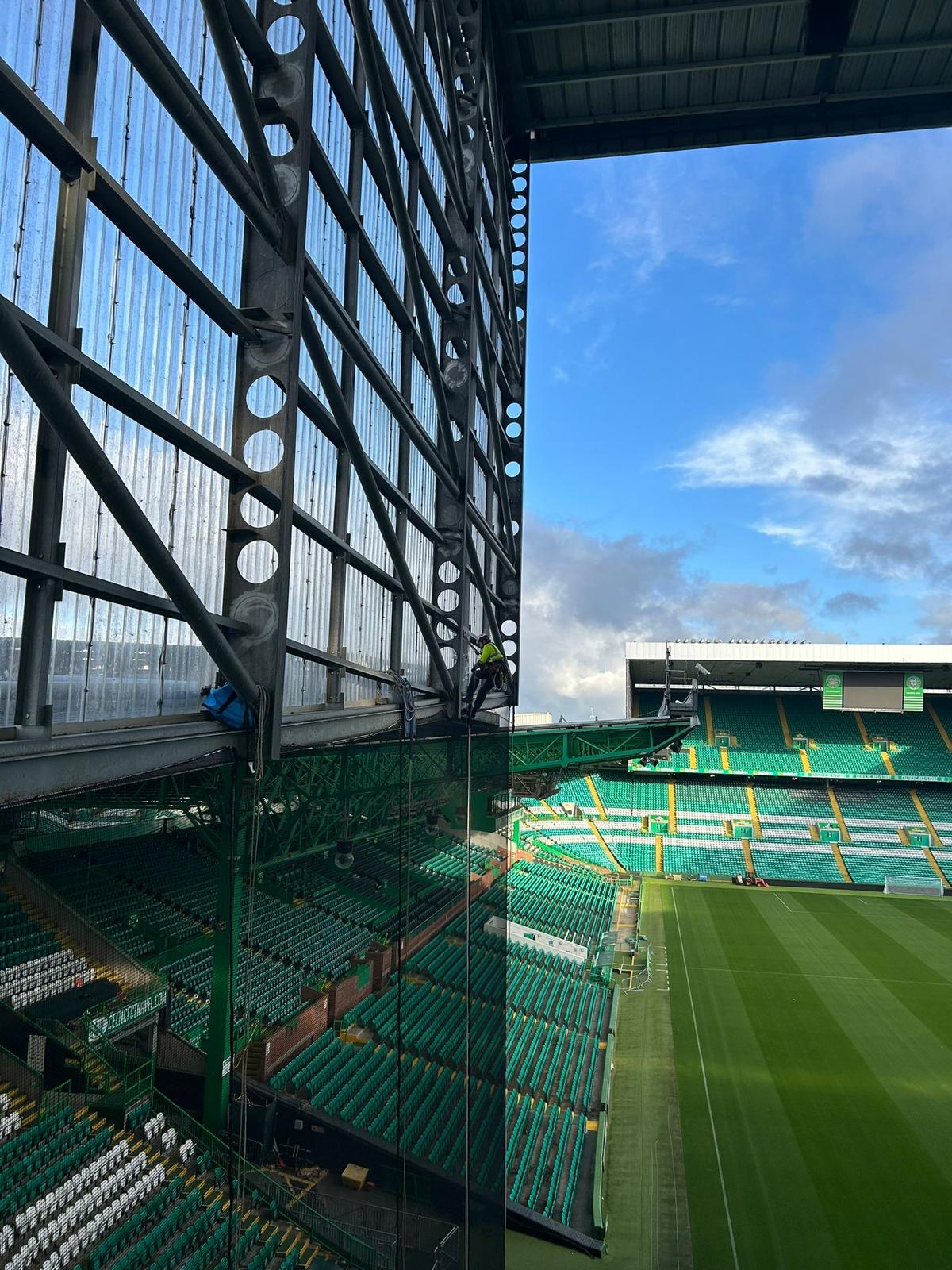 Roofing Advisors rope access operatives installing fan segregation netting from the roof structure at Celtic Park, Glasgow