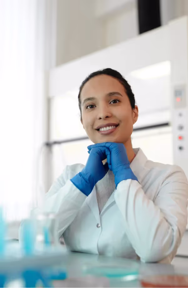 a woman in lab suit and gloves smiling