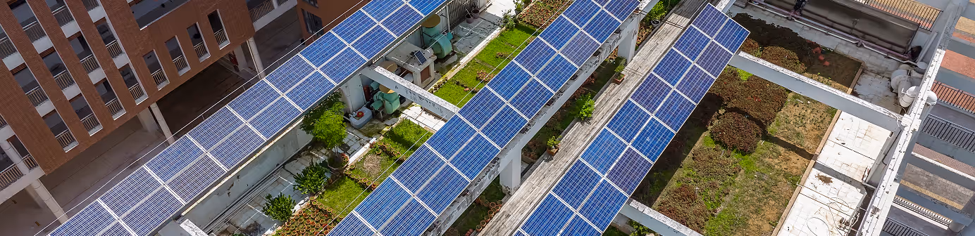 Aerial view of a green building with solar panels and rooftop gardens, showcasing sustainable urban infrastructure.