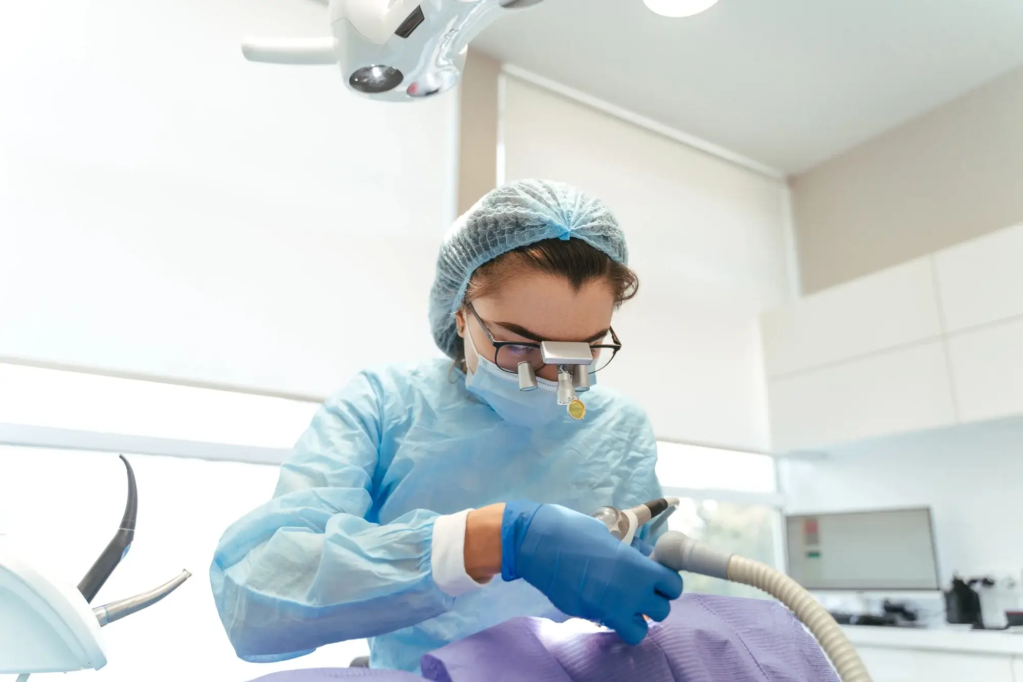 Dentist performing treatment wearing protective gear dentist in Fort Worth