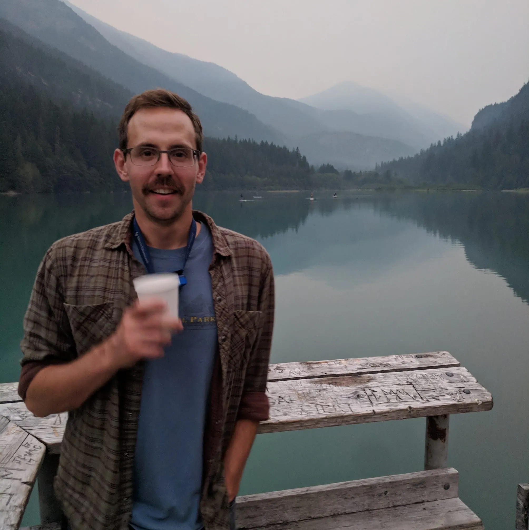 A man with a beard and glasses is holding a cup of coffee.