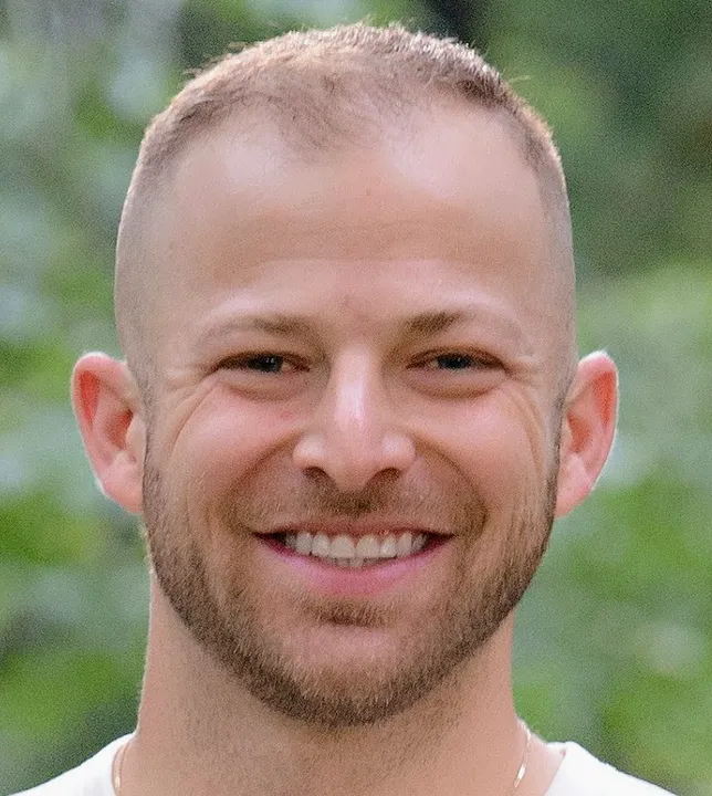A man with a shaved head smiling for the camera.