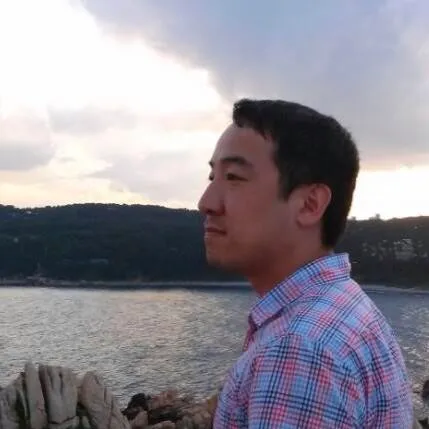 A man wearing a plaid shirt and looking out at the ocean.