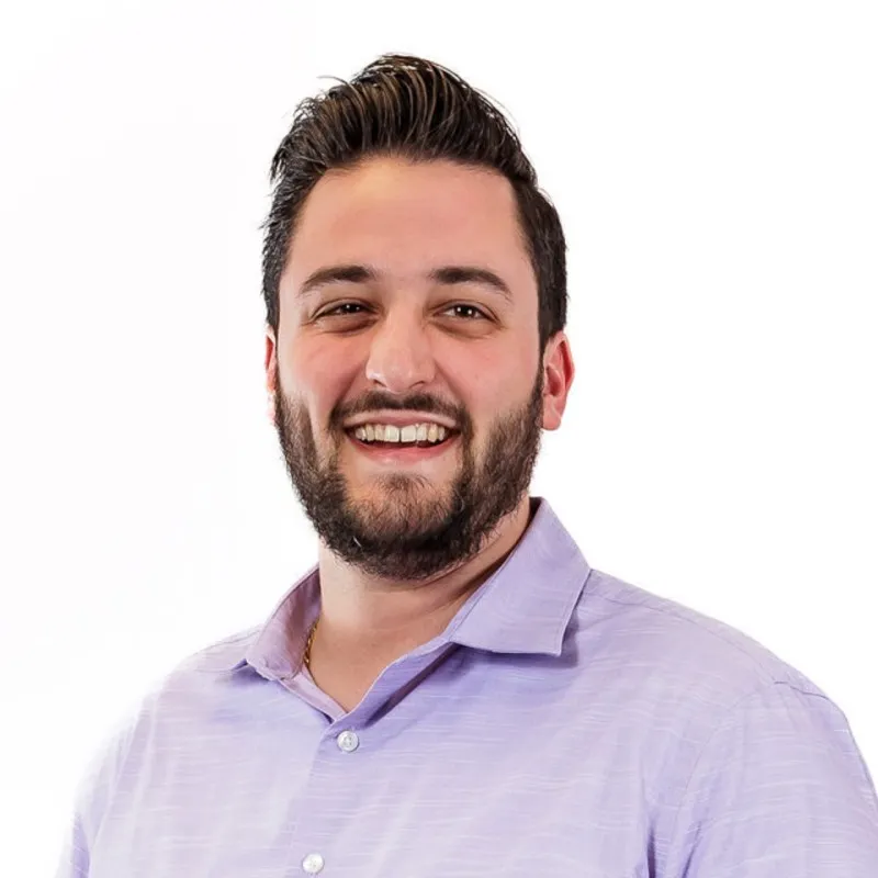 A man wearing a purple shirt and smiling.