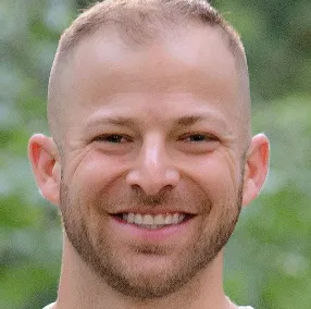 A man with a shaved head smiling for the camera.