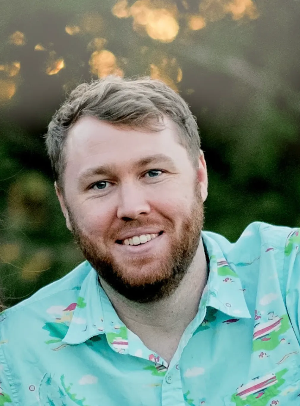 A man with a beard and a blue shirt smiling at the camera.