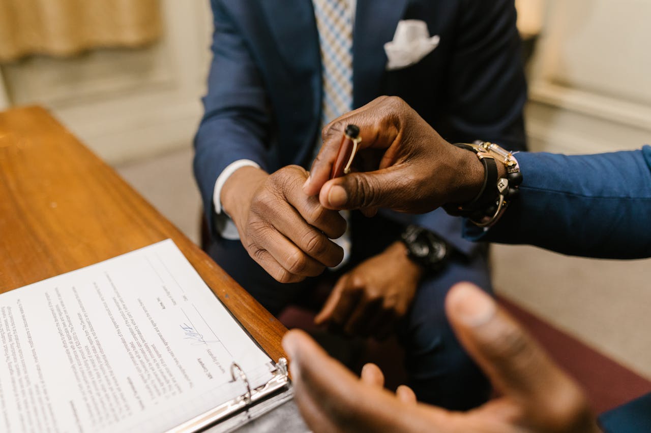 Close-up of Man Handing a Pen to Another Man to Sign the Documents