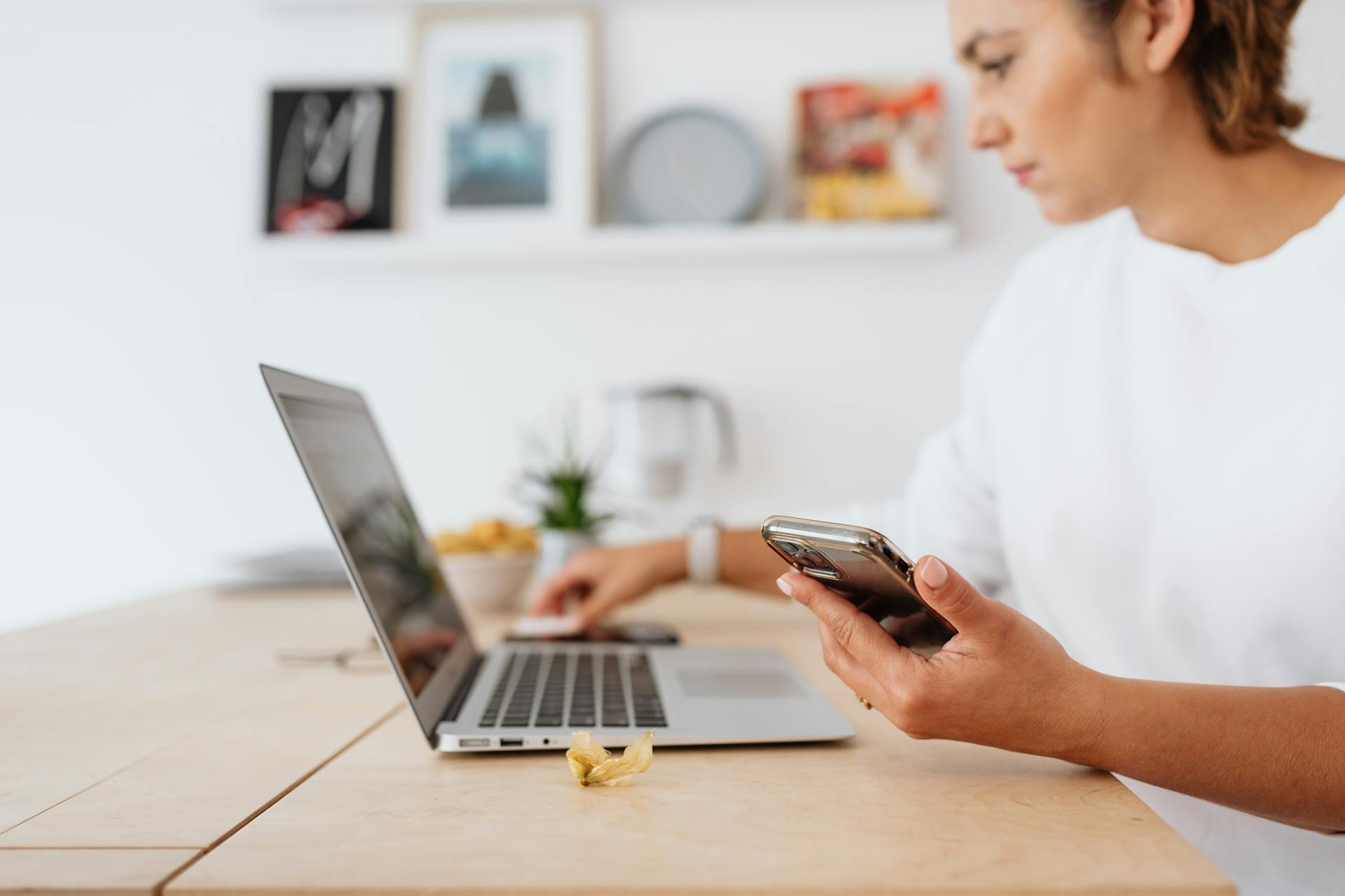 Person Holding Smartphone While Sitting In Front of a Laptop