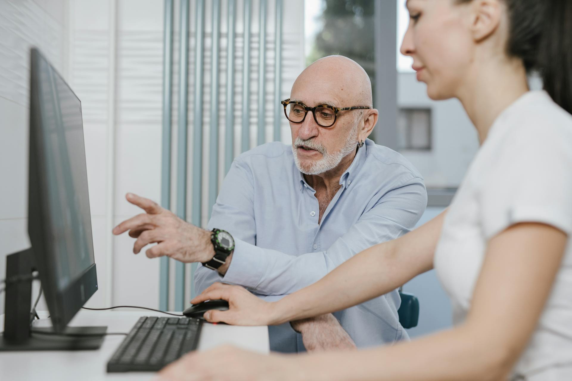 Elderly Man wearing Eyeglasses pointing on the Screen