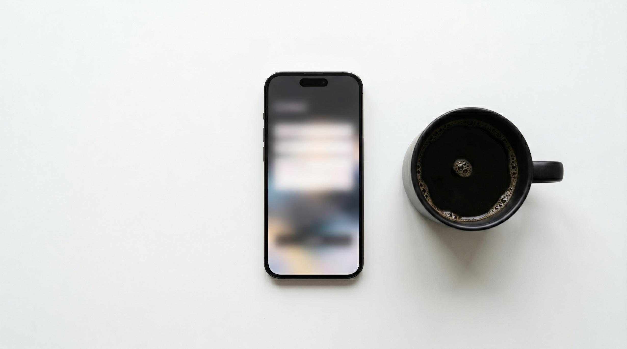 overhead flat-lay photograph of a smartphone face-up on a white desk surface, screen showing a blurred contact form page.