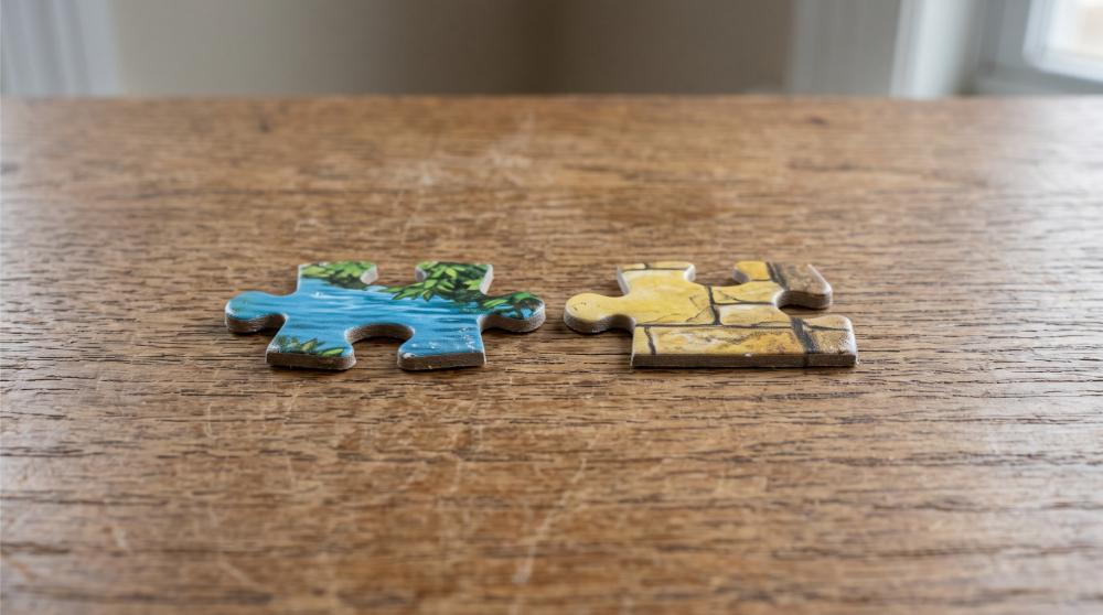 still life photograph of two mismatched puzzle pieces on a plain wooden surface