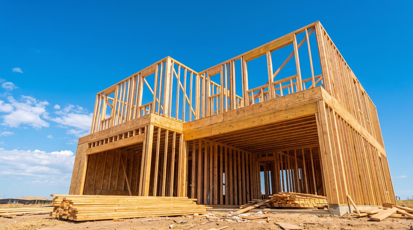 New home construction framing against a bright blue sky