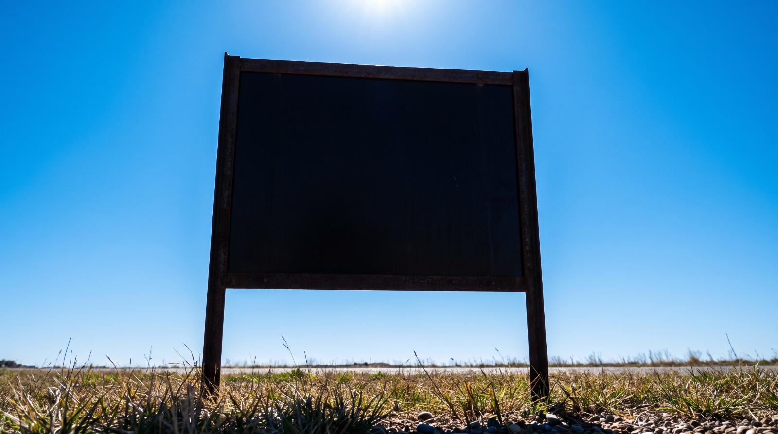a single yard sign silhouetted at a low angle against a bright clear blue sky