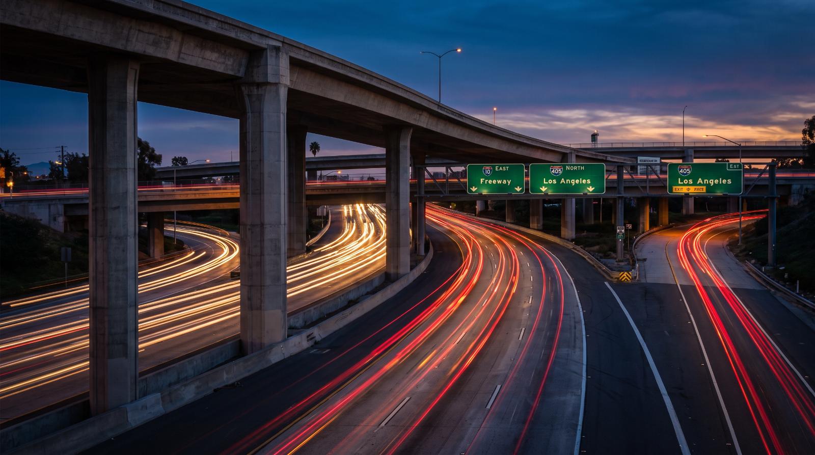 Traffic light streaks on a California freeway interchange at dusk