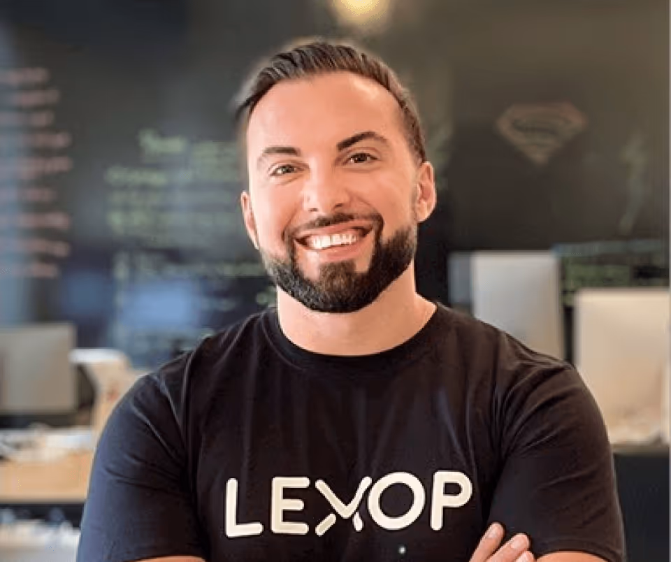 Lexop CEO Amir Tajkarimi  pictured from chest up. He's smiling with arms crossed, wearing a black t-shirt with Lexop written on it.
