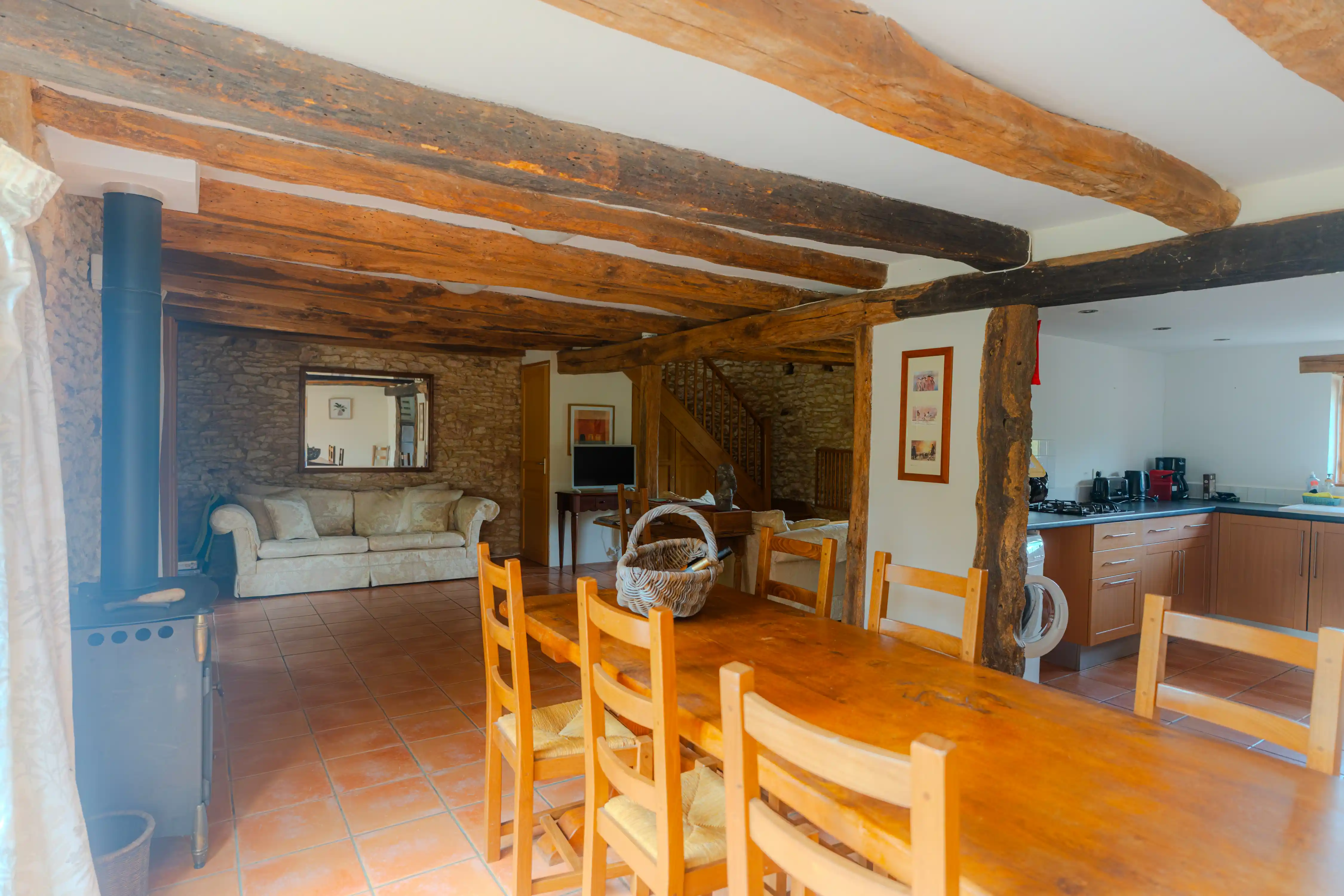 Photo de l'intérieur du gîte Mimosa de 8 personnes : salon, salle à manger et un bout de cuisine et du poêle à bois.