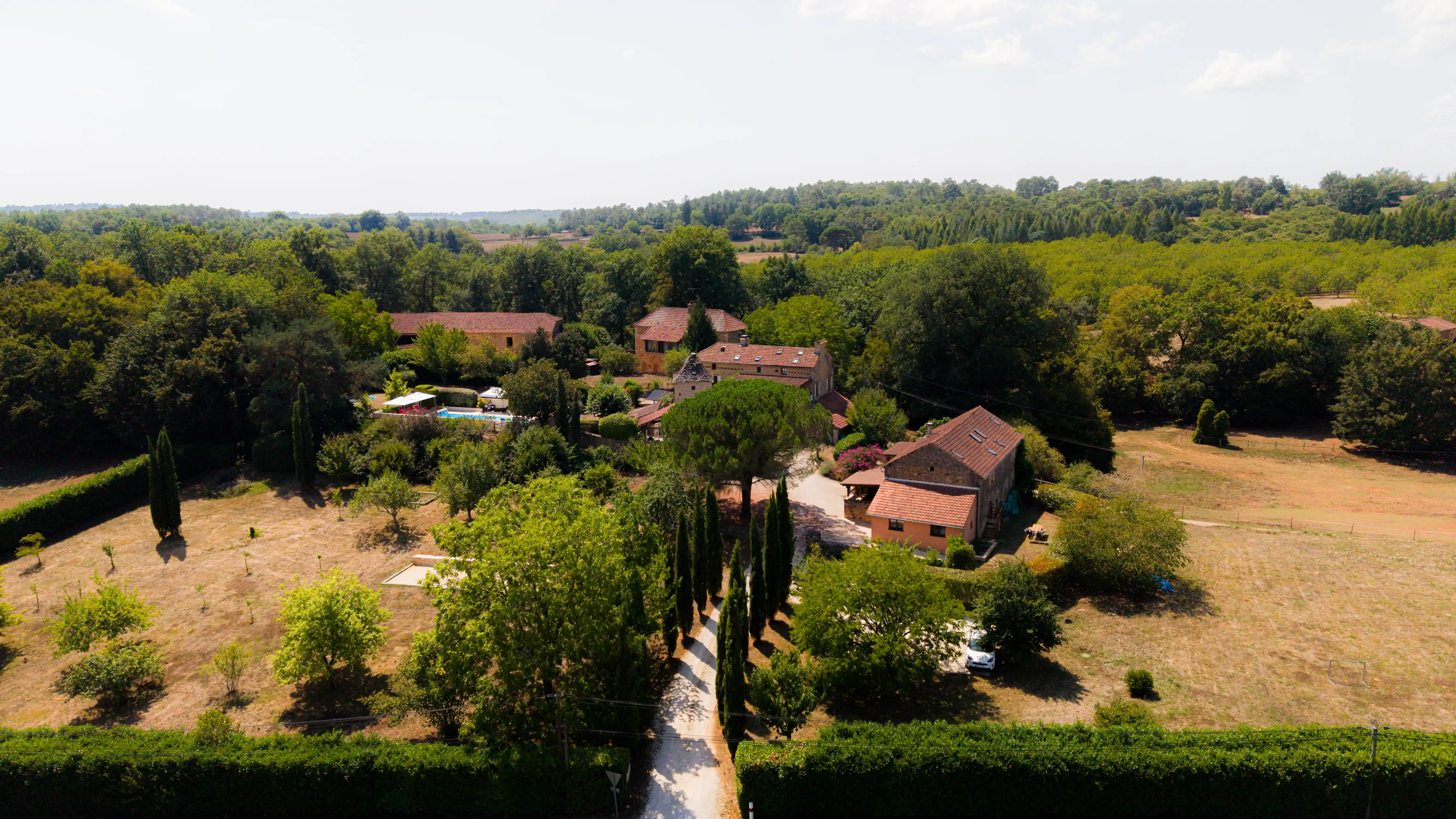Photo au drone de du Domaine du Pigeonnier prise depuis l'entrée, avec : l'allée de cyprès, le pigeonnier, les gîtes