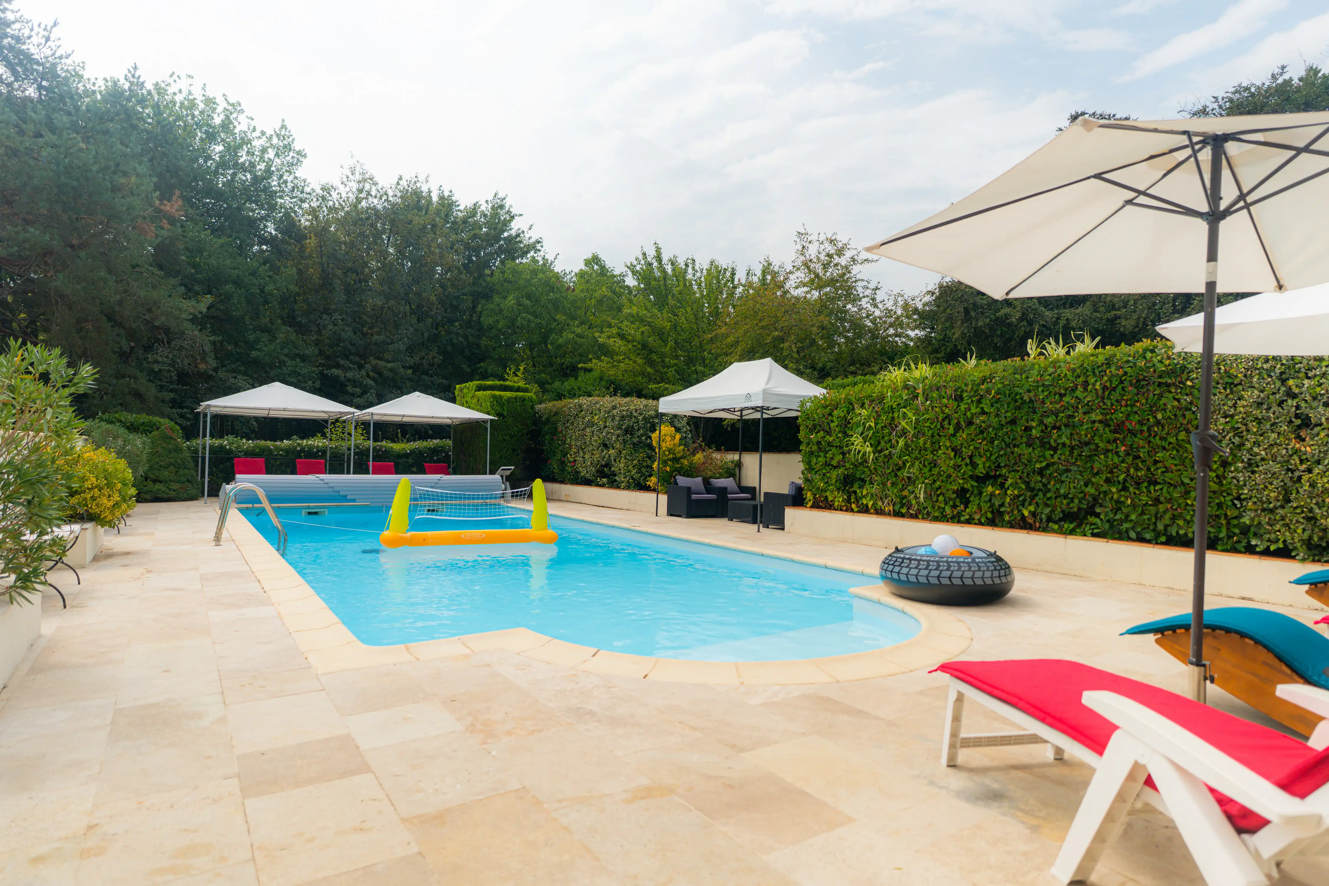 Photo de la piscine, des transats, parasols et jeux d'eau.