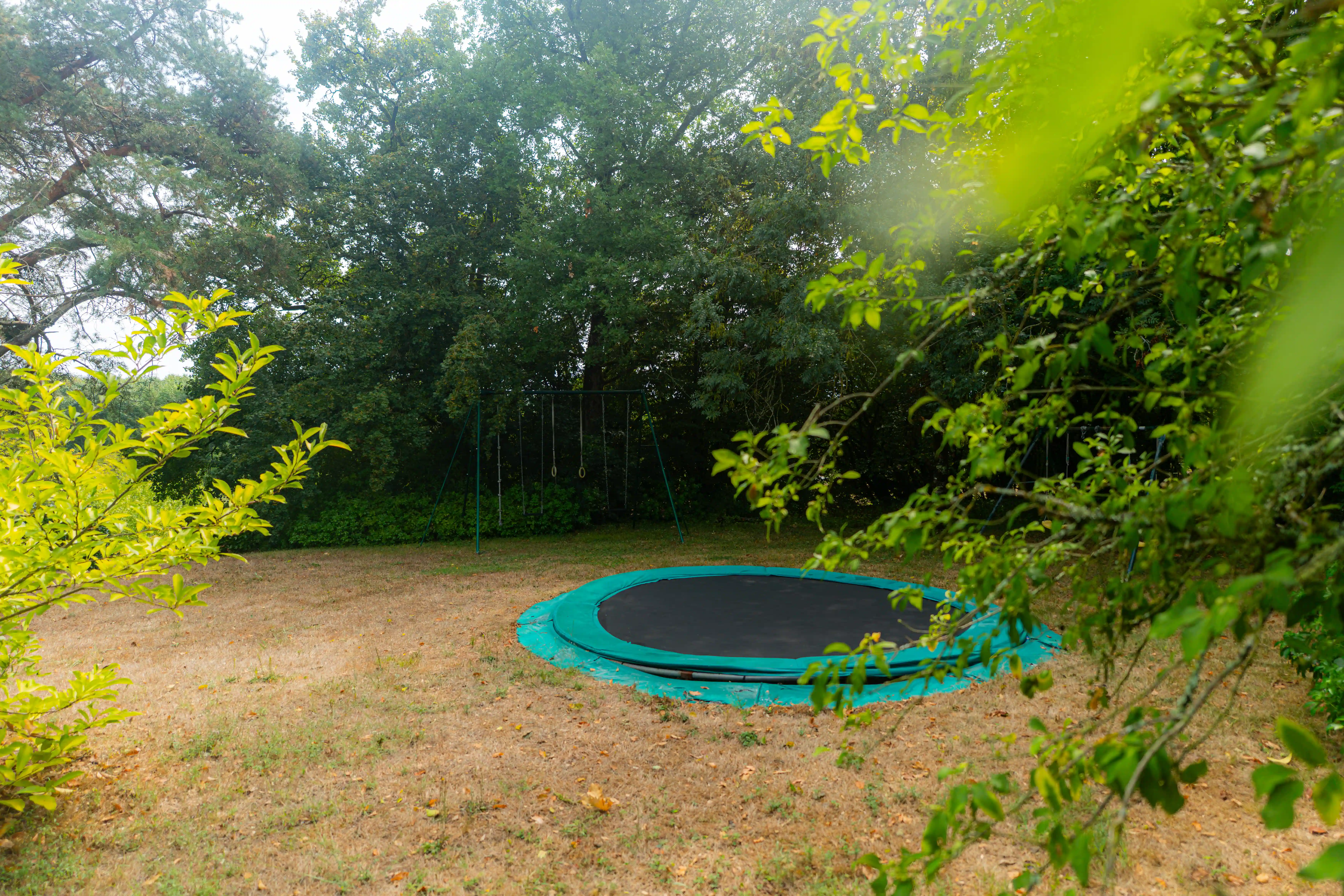 Photo de l'aire de jeu avec trampoline et balançoires
