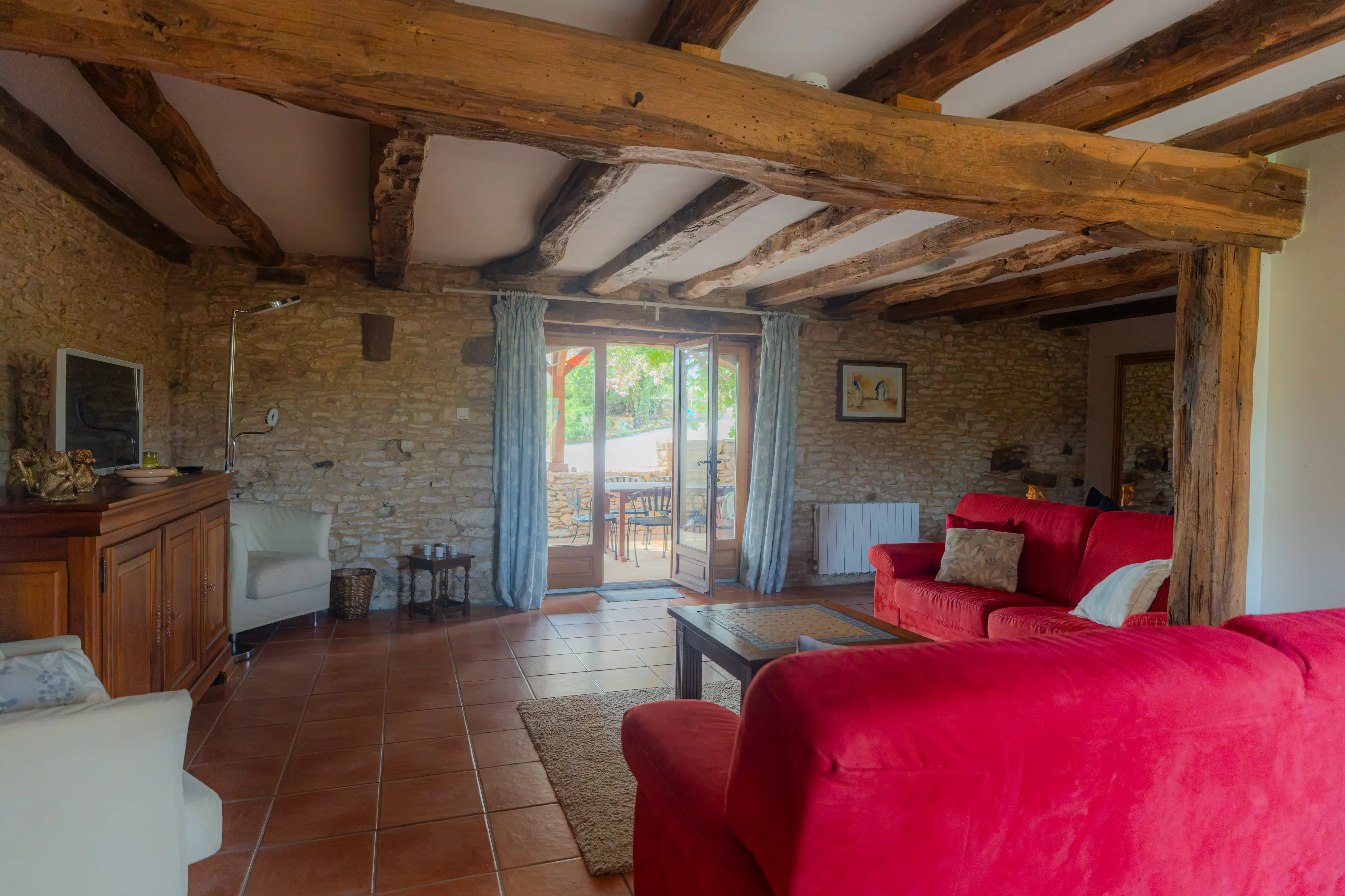 Photo de l'intérieur du gîte Magnolia de 6 places : salon, TV et vue sur la terrasse.