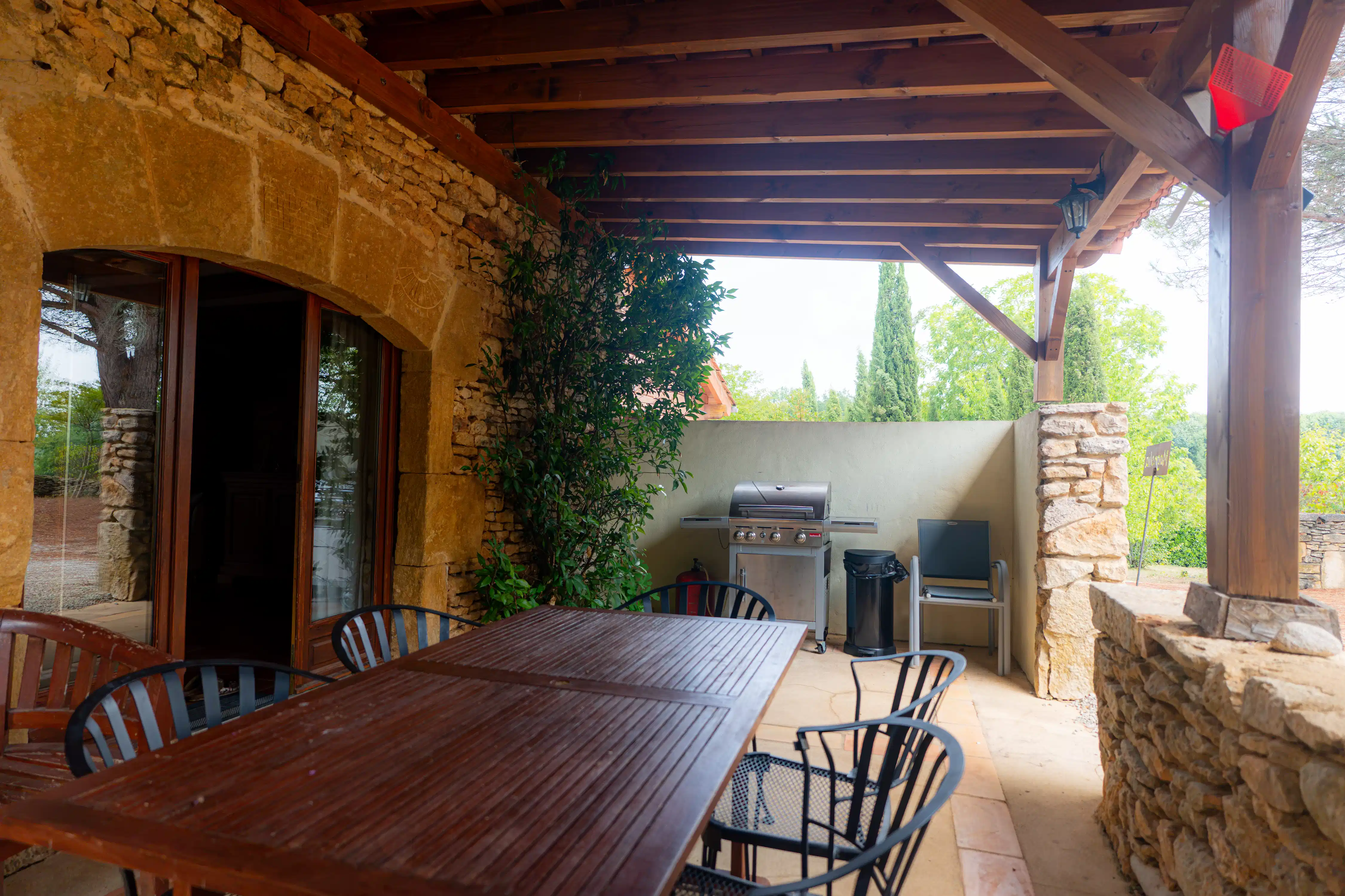 Photo de l'extérieur du gîte Magnolia de 6 places : terrasse couverte privée avec table, chaises et barbecue.