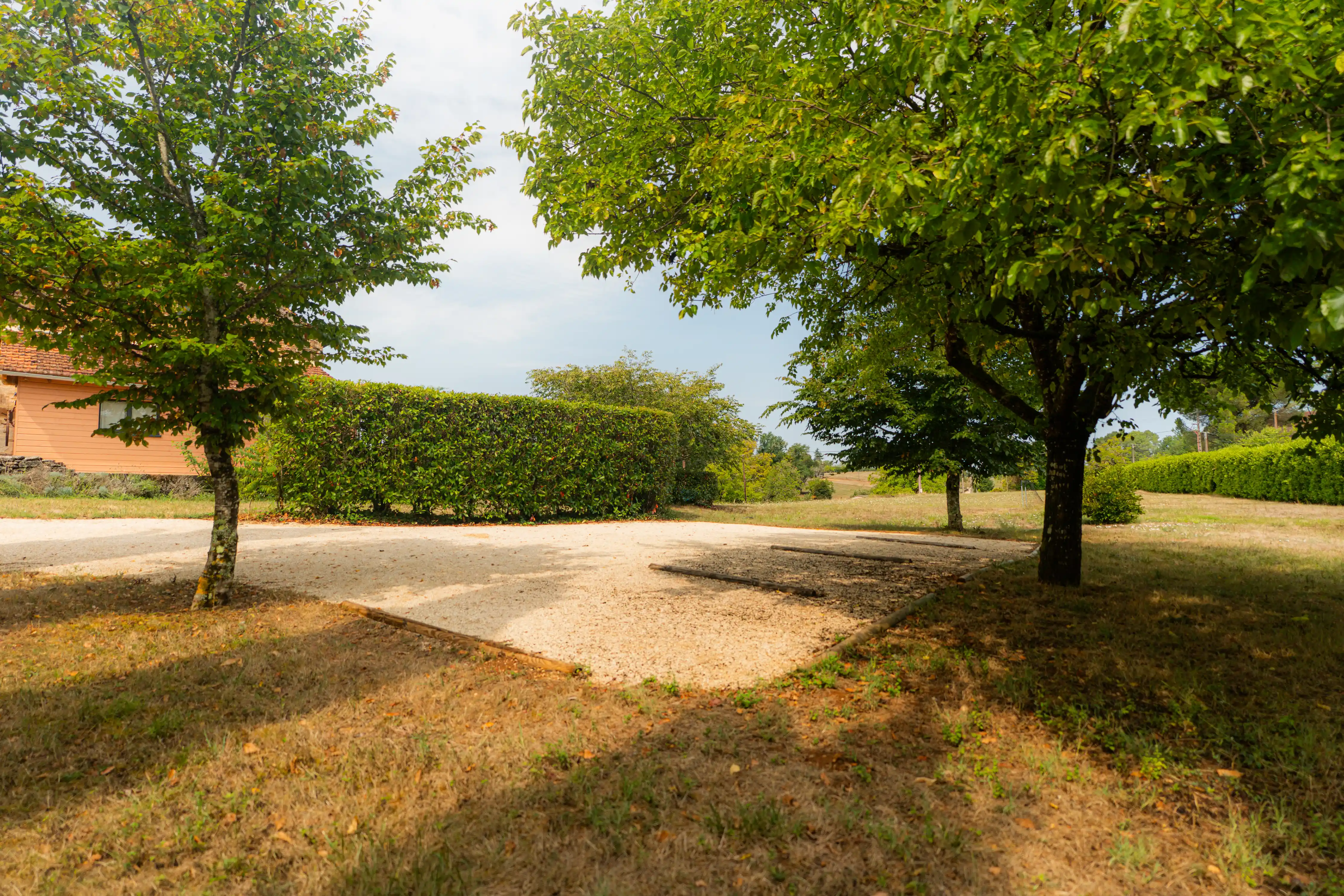Photo du parking privé pour les gîtes, avec 4 places entre les arbres