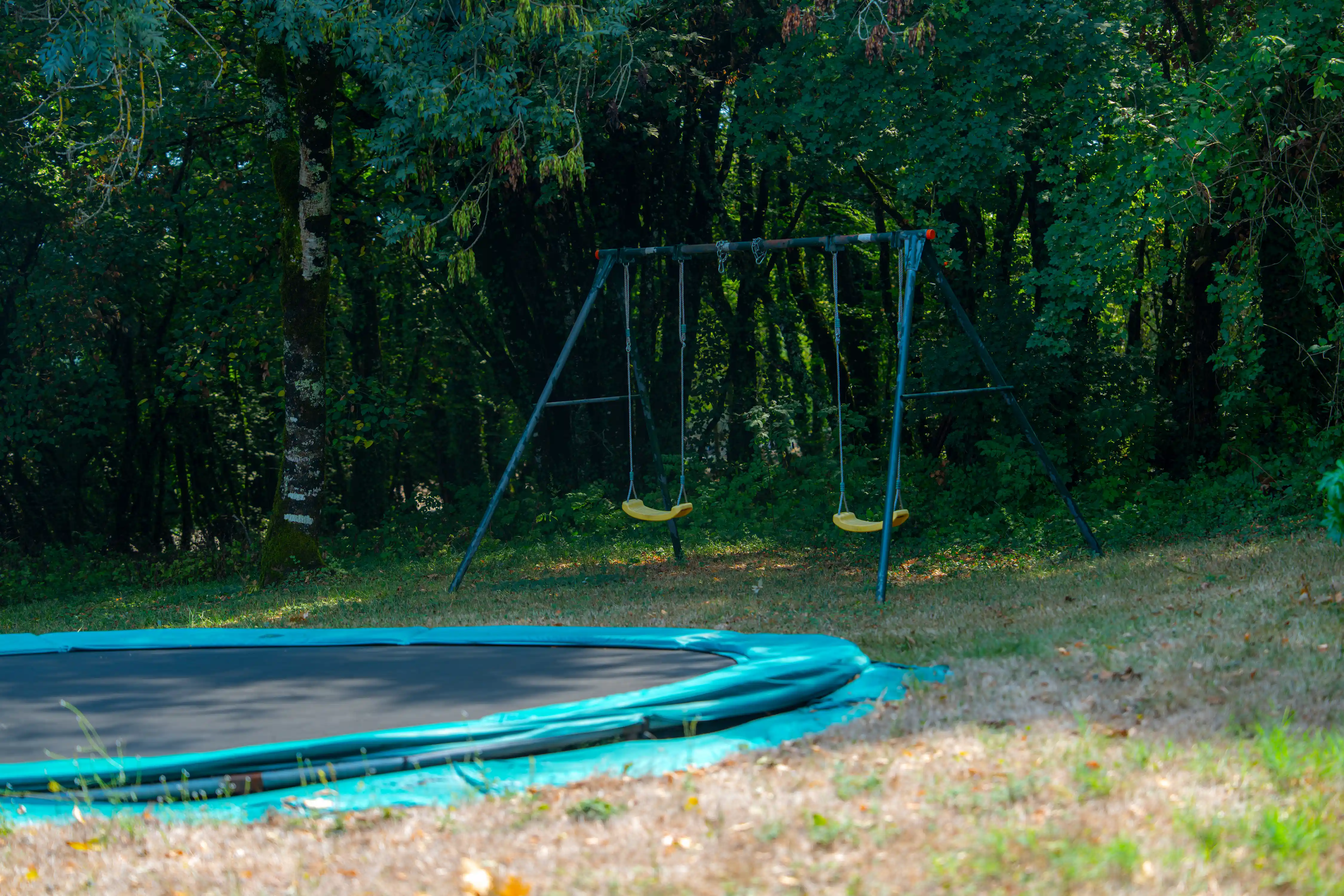 Photo de l'aire de jeu avec trampoline et balançoires