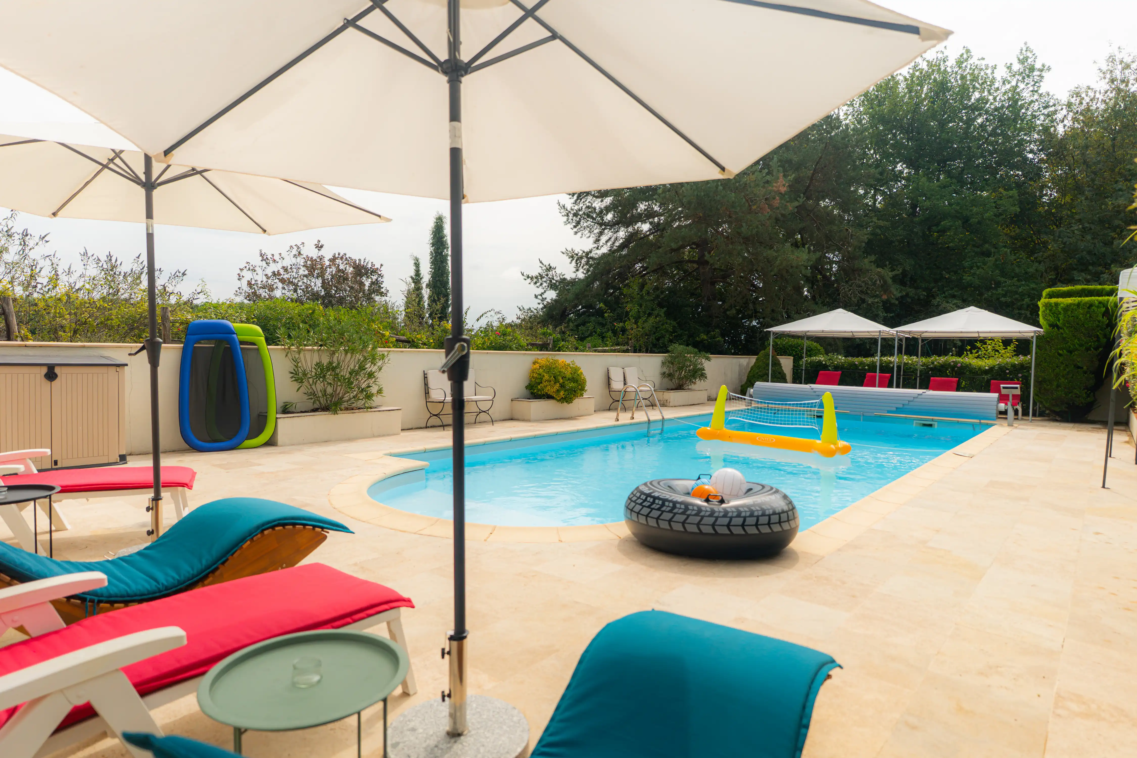 Photo de la piscine, des transats, parasols, bouées et jeux d'eau.