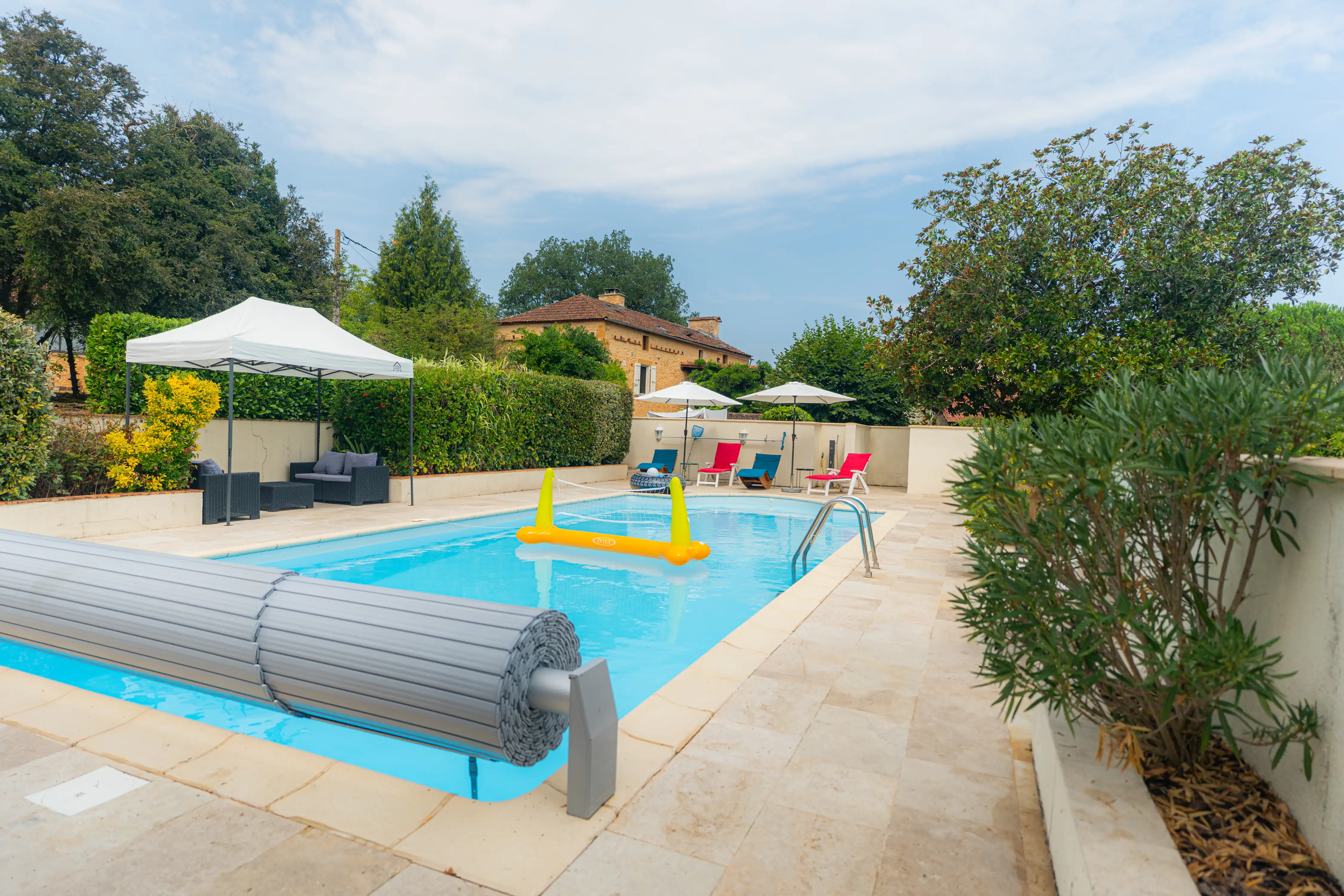 Photo de la piscine, des transats, parasols et jeux d'eau.
