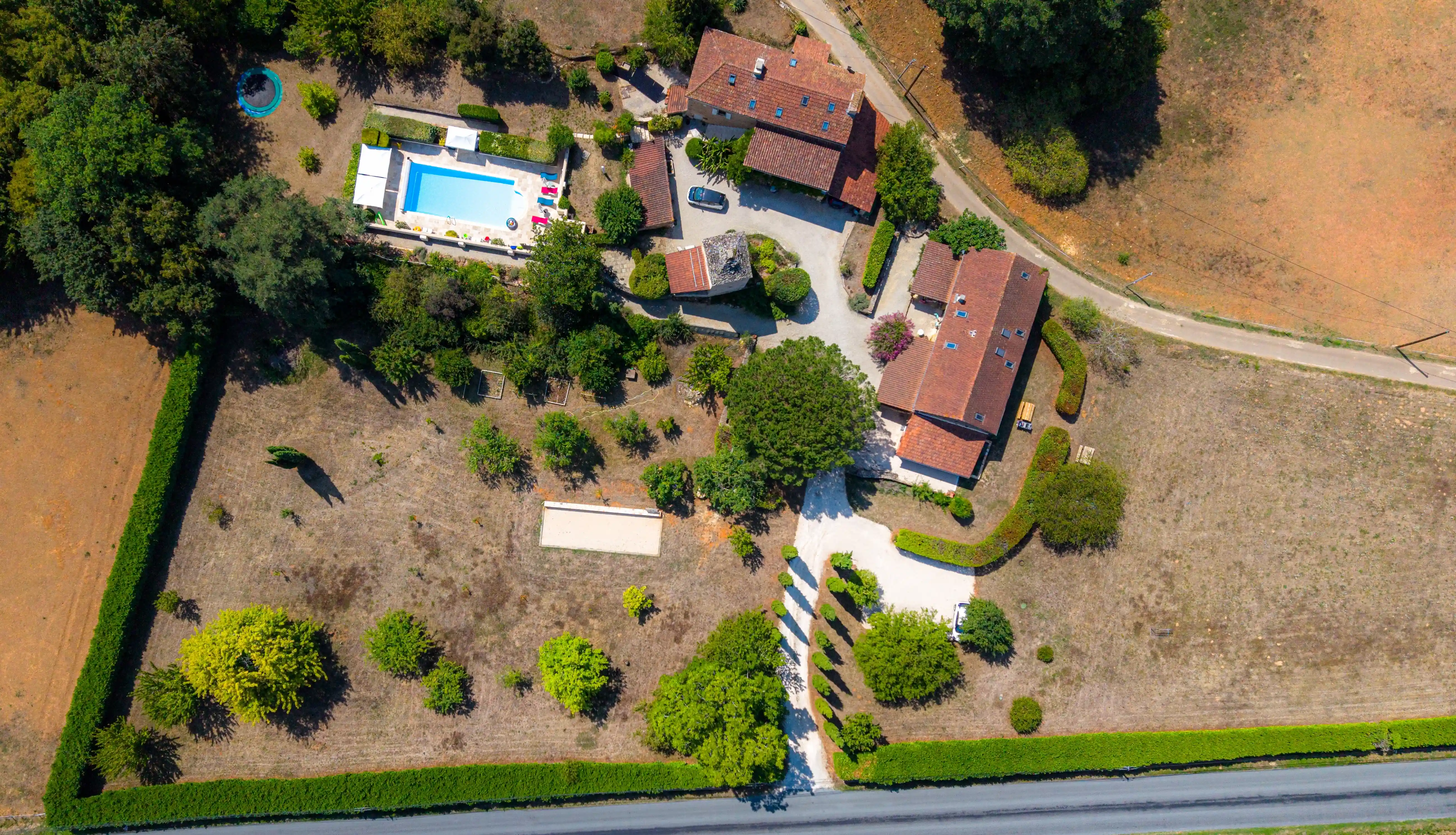 Photo drone top shot du Domaine du Pigeonnier avec : pigeonnier, piscine, verger, aire de jeu, terrain de pétanque, parking et gîtes.