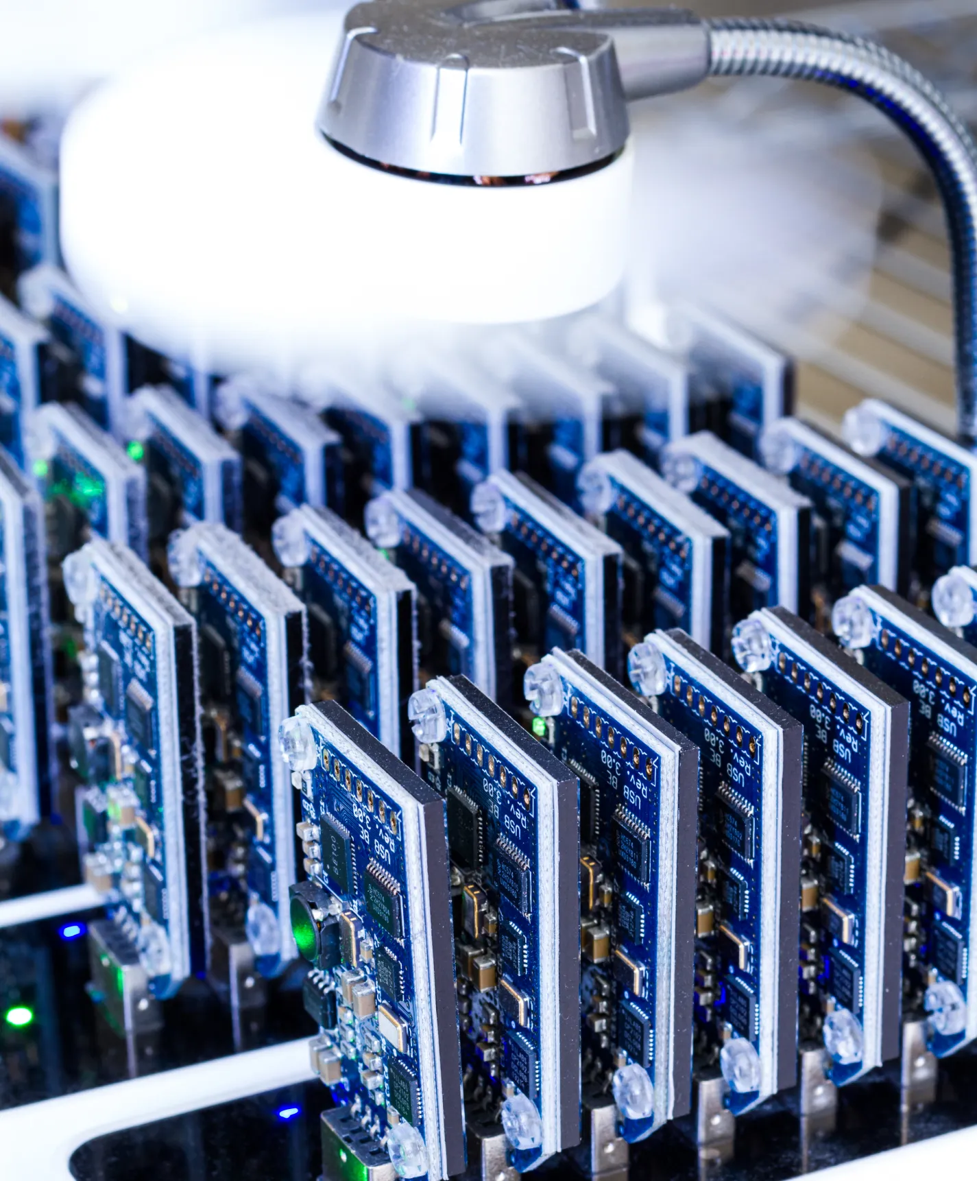 Rows of blue circuit boards with electronic components connected on a server with a cooling system emitting mist above.