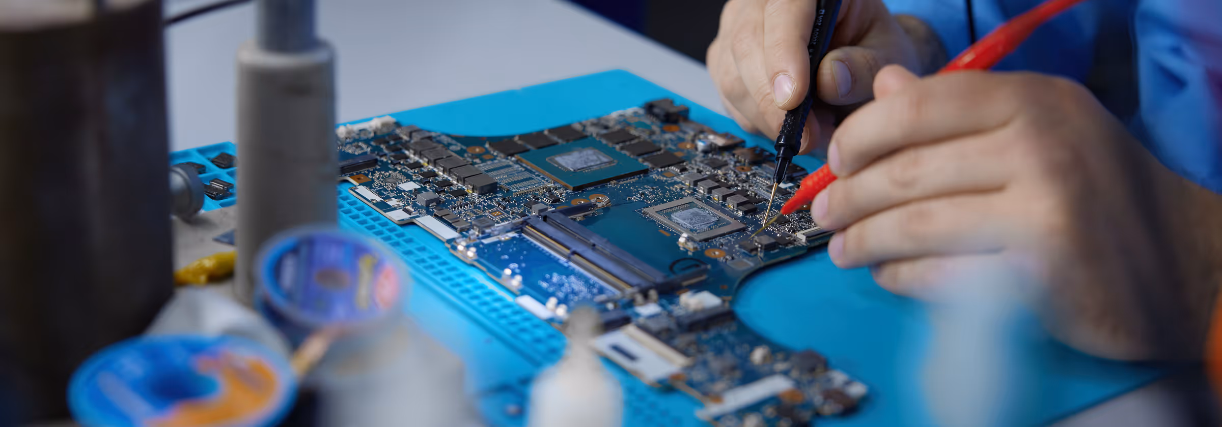 Technician using probes to test or repair components on a circuit board.