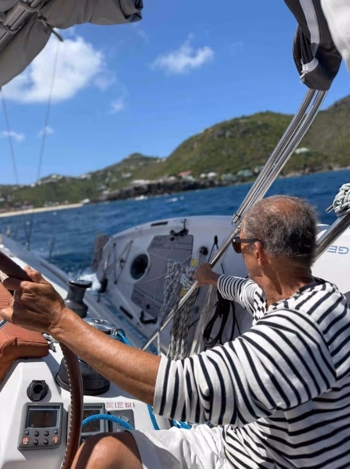 Navigation initiation à la voile avec sailin'soun. Un voilier en mer près d'une île verdoyante sous un ciel bleu.