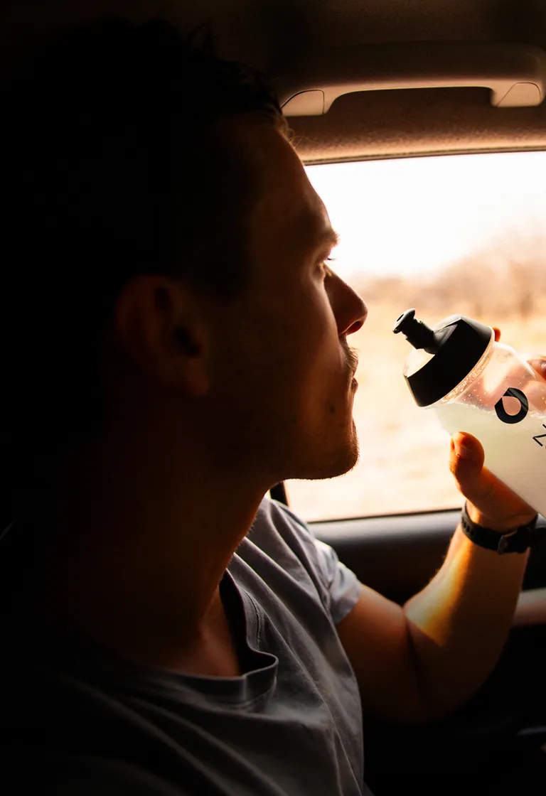 Homem bebendo LIQUIDZ dentro do carro em viagem