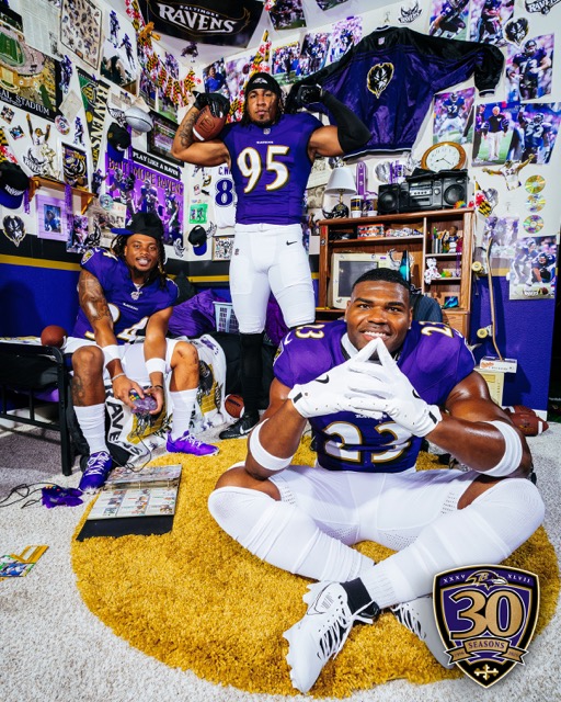 This image shows three of the Baltimore Ravens, posing energetically in a room completely covered with Ravens memorabilia.