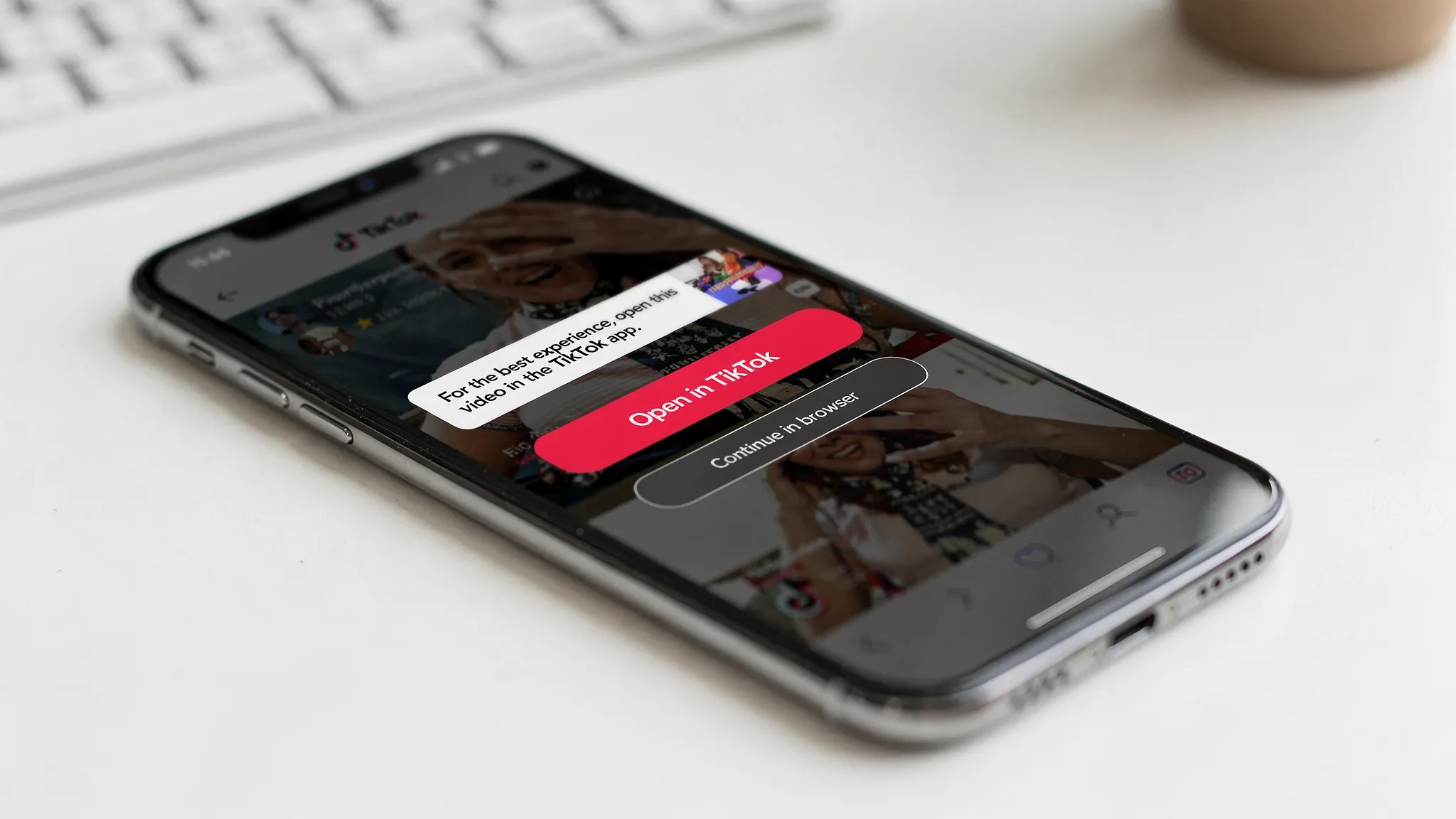 A smartphone showing a mobile browser on a TikTok video page with a prominent “Open in TikTok” button, plus a secondary “Continue in browser” option and a small banner explaining the app handoff.