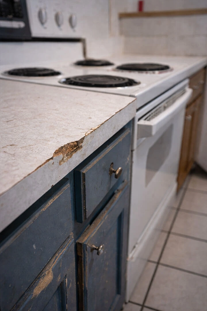 Worn kitchen with damaged countertop and cabinets
