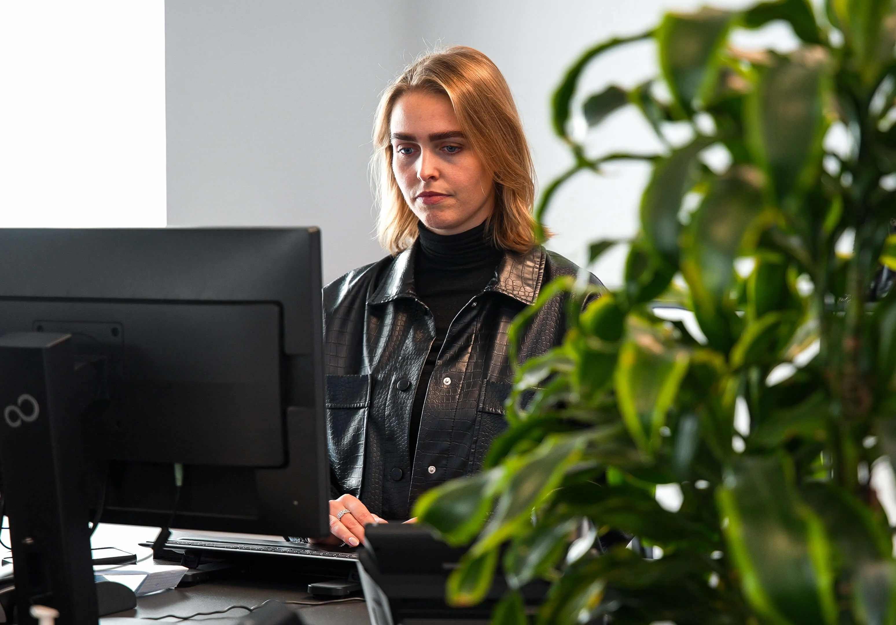 Woman standing at her desk looking into a computer