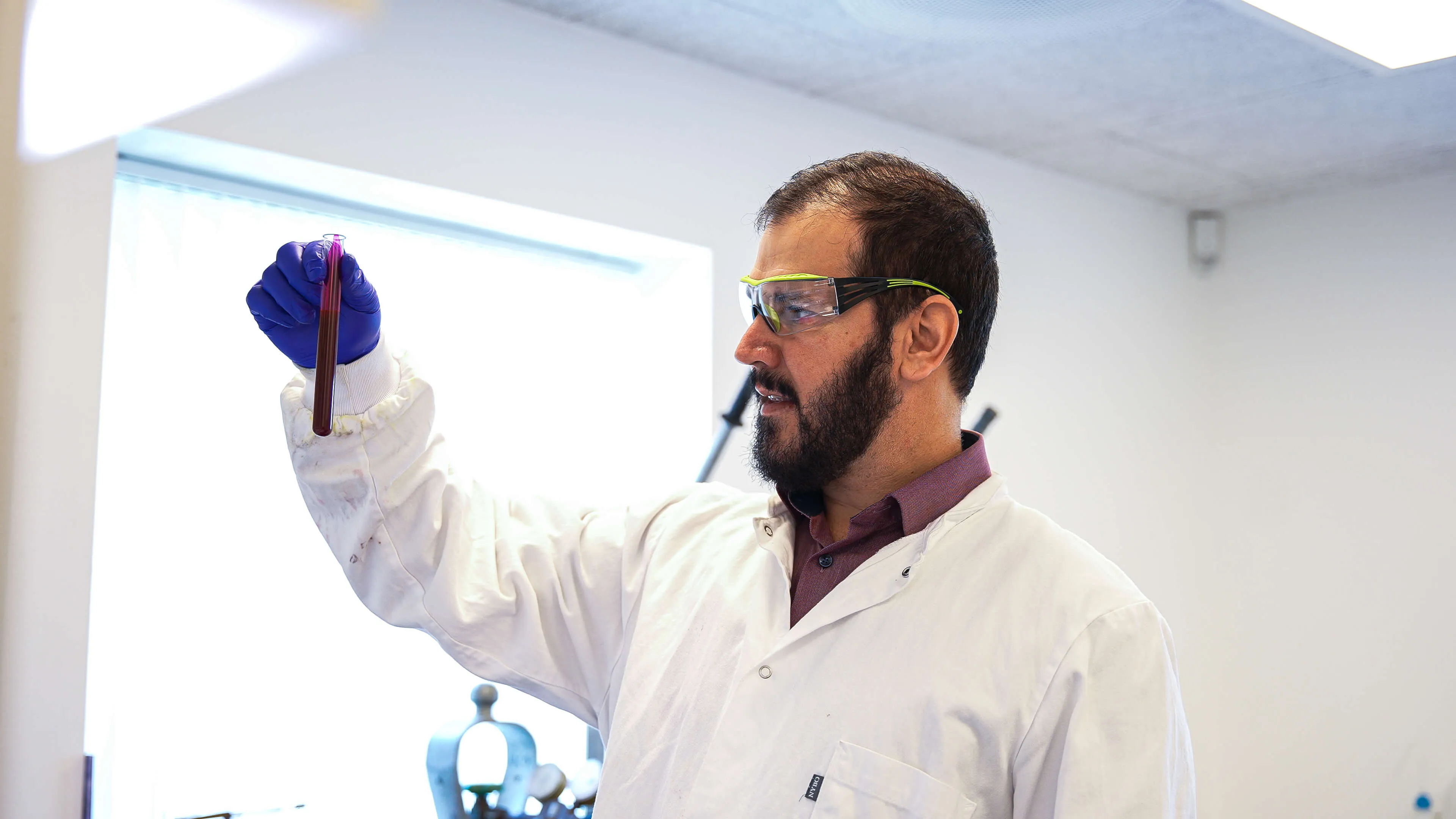 A man standing with a glass in his hand in a labratory