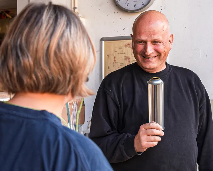 A man with an aerosol can in the hand talking to a woman 