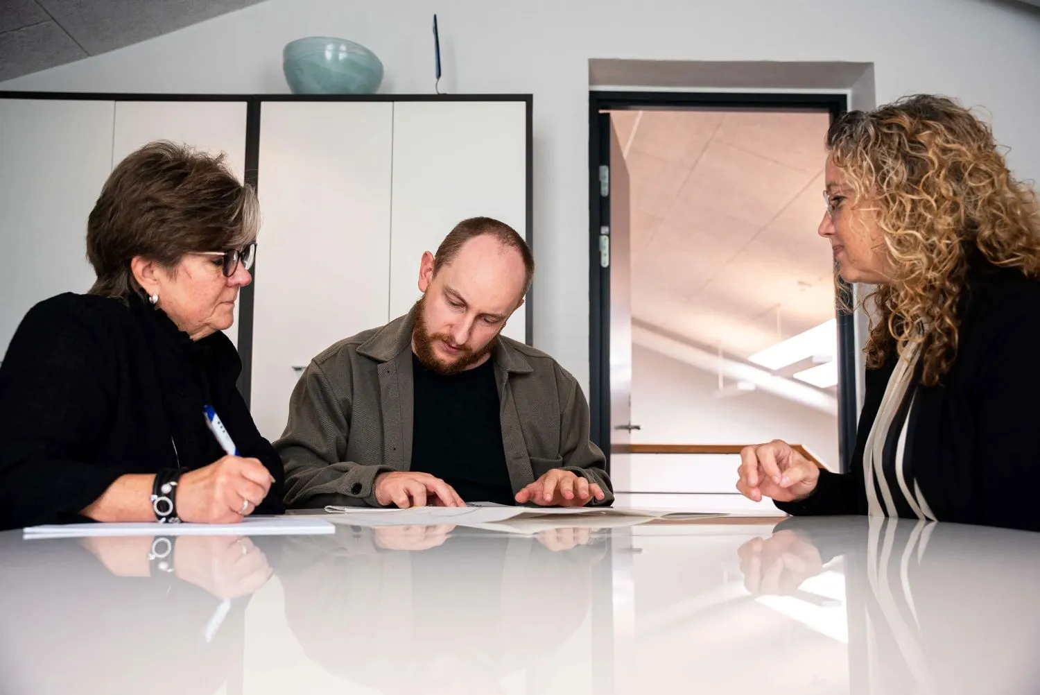 A man and two women sitting at a table looking at papers