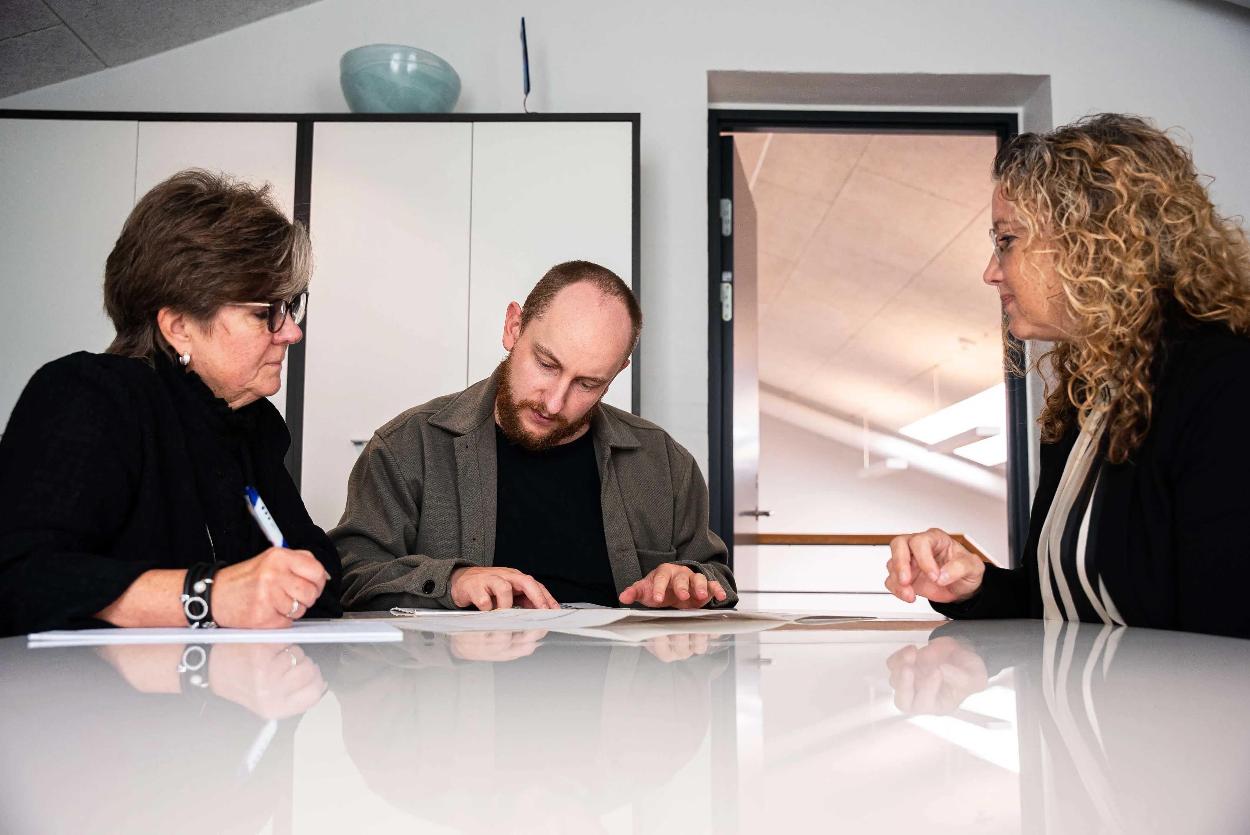 A man and two women sitting at a table looking at papers