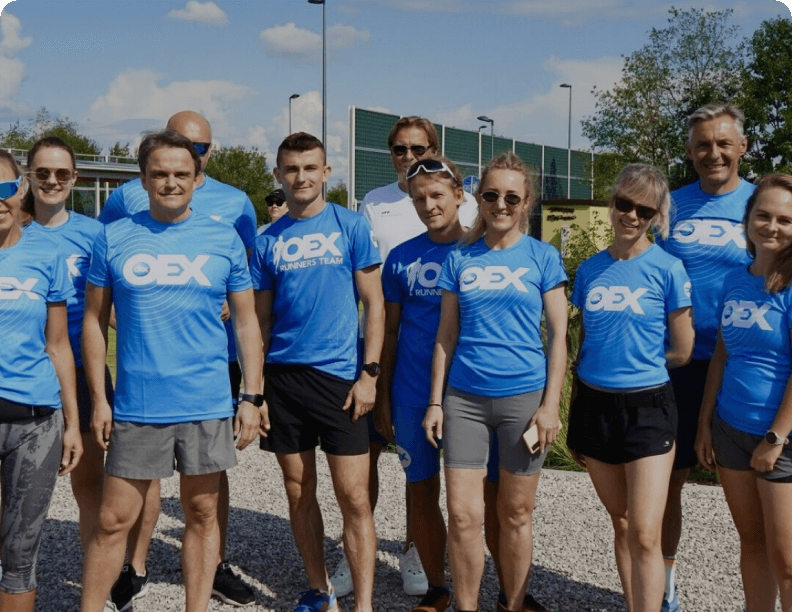 OEX employees taking part in the Poland Business Run, standing together outdoors in branded shirts.