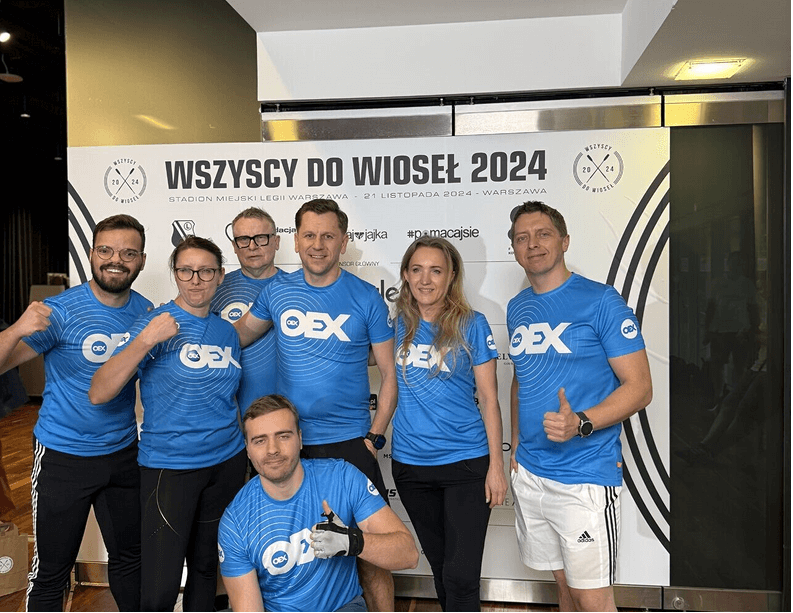 OEX team members in blue shirts celebrating the Wszyscy do wioseł rowing event 2024.