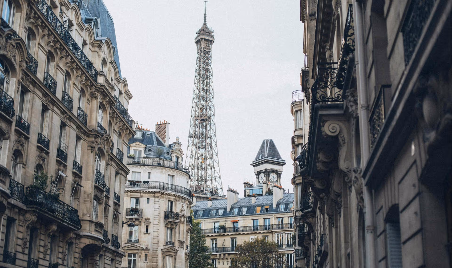 Eiffel Tower seen from a Paris street with classic Haussmann buildings