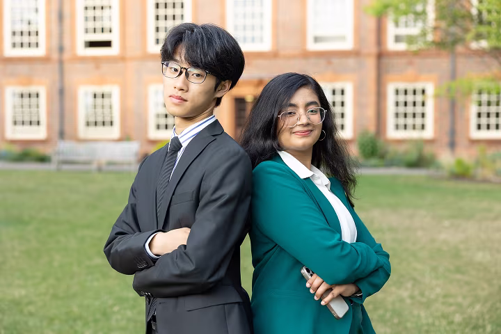A group of diverse students clapping and smiling enthusiastically in a classroom setting.