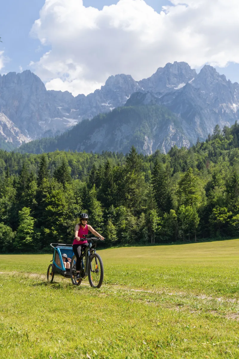 Mom driving a child in front of moutain Špik in Gozd Martuljek