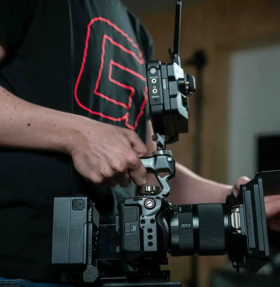 Graphrs videographer adjusting camera rig components to prepare for filming